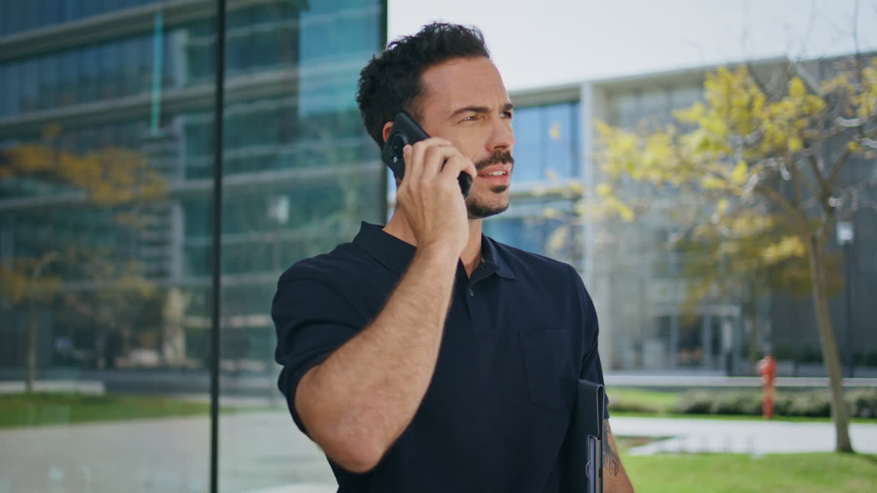 Serious guy talking phone at office building background close up. Man saying no
