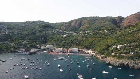 Aerial-drone-shot-of-Amalfi-Coast,-Punta-Campanella-Natural-Park,Italy-with-the-view-of-resorts-on-the-side-of-beach-on-a-sunny-day