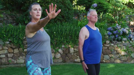 pareja de ancianos caucásicos realizando ejercicios de estiramiento juntos en el jardín
