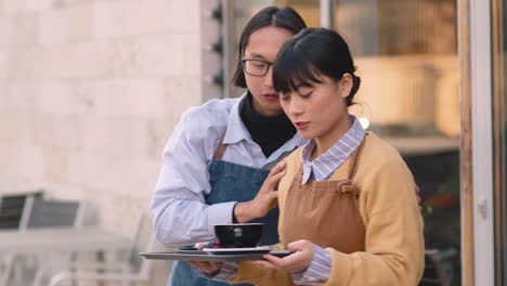 serveuse douteuse tenant un plateau de nourriture à l'extérieur du café pendant que son collègue masculin la dirigeait vers la table pour servir