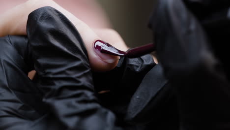 applying dark red nail polish