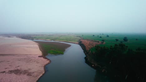 river winding through a green landscape at dawn, misty air, aerial view