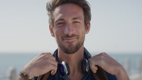 retrato de un joven feliz, un turista sonriente disfrutando de un cálido día de verano en la orilla del mar, el viento soplando el cabello en cámara lenta