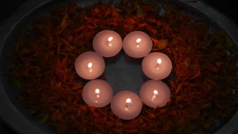 focus shift with a man's hand picking up and placing a diya between tealight candles. diyas or lamps lit up for diwali 'festival of light', the most important ancient hindu festival