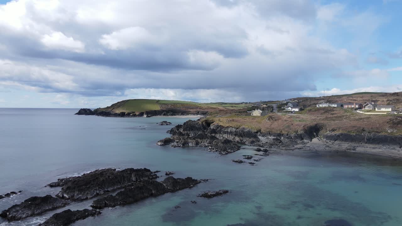 Coastal area from above, slide footage over beautiful calm ocean with the view on rugged coast with holiday homes, sandy beaches