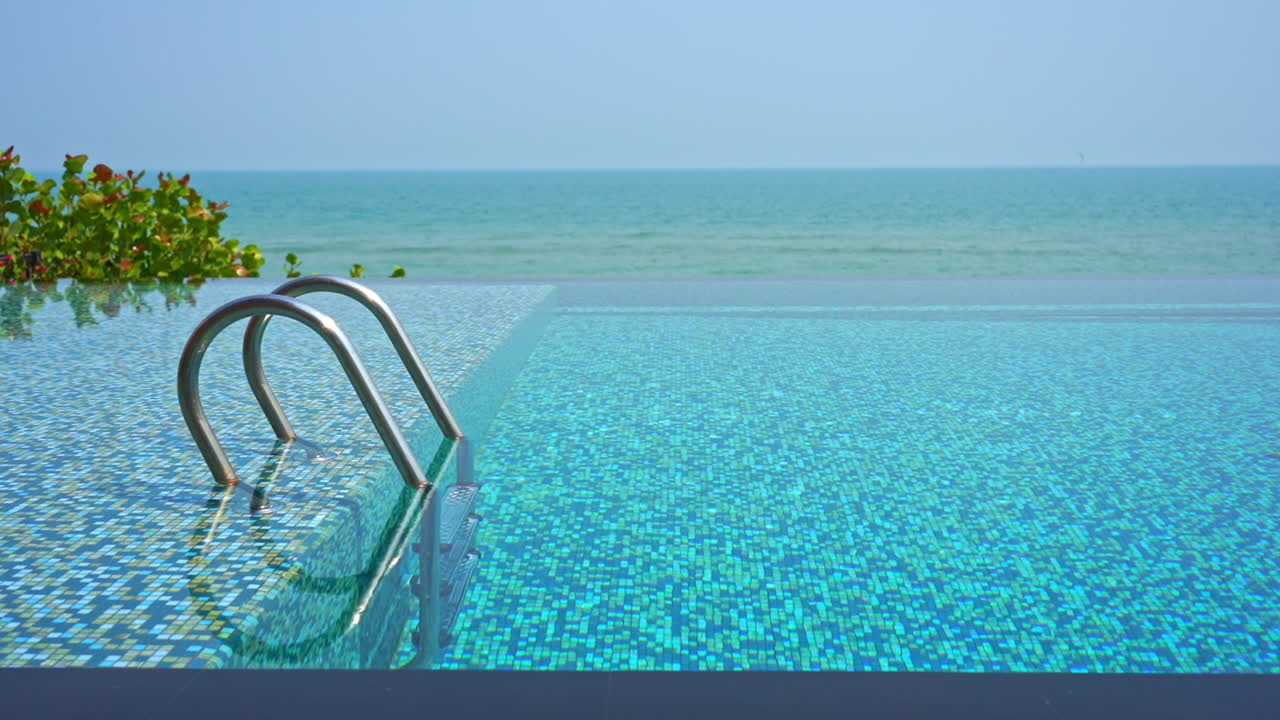 Empty infinity pool, steps, blue water and amazing view of tropical sea horizon, slow motion full frame