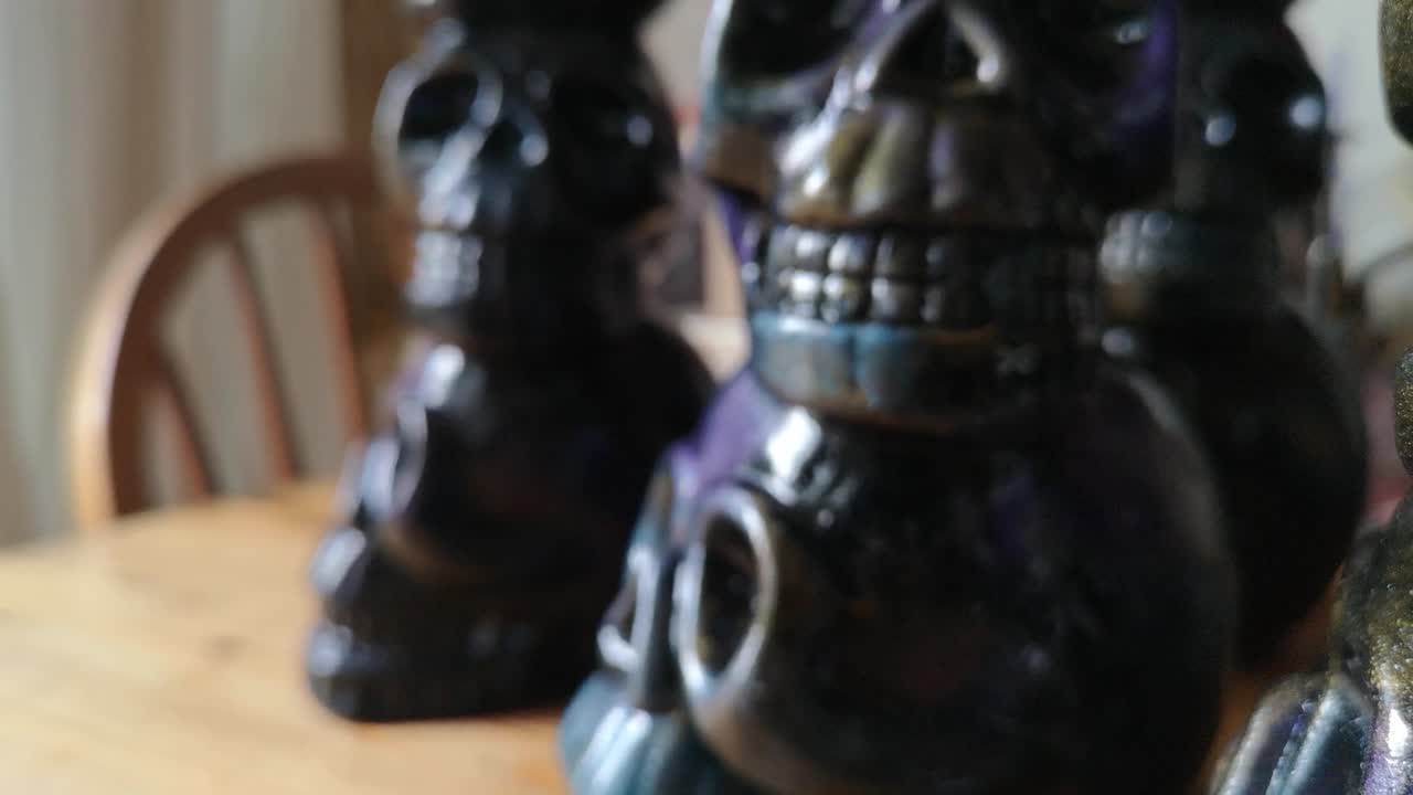 Colourful painted ceramic spooky death skull totem crafts pottery ornament shallow dof reverse shot