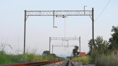 Old-wires-hang-down-over-decommissioned-rural-railway-track,-S-Africa
