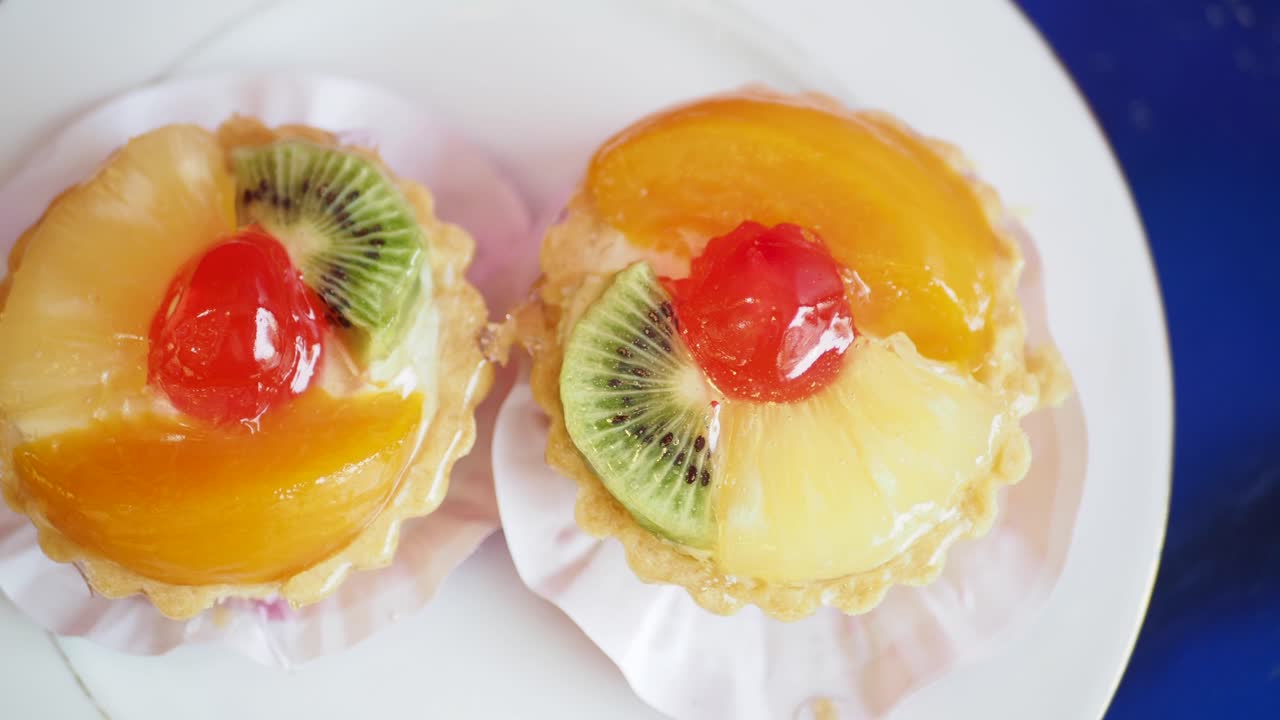 Two colorful fruit tarts on a white plate