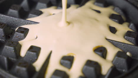 vista macro de cerca de la masa de gofres recién preparada llenando la máquina para hacer gofres calientes para el desayuno de la mañana