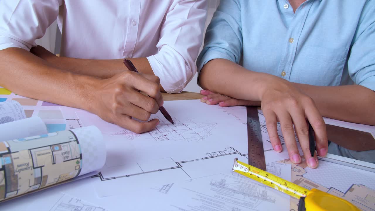 Hands Of Two Architects Who Draw Something In A House Plan