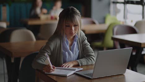 young beautiful smiling asian business woman holding a coffee and laptop placed at the wooden table at the office. woman checking mail or researching while telecommuting