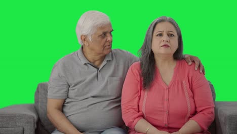 una vieja pareja india triste viendo la pantalla verde de la televisión.