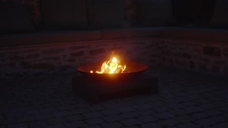 Closeup-of-flames-in-a-fire-bowl-flickering-on-a-gentle-wind-outdoors-at-night-illuminates-atmospheric-backyard,-creating-a-cozy-and-tranquil-scene