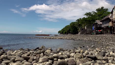 Outrigger-boat-floating-near-a-poor-fishing-village-on-a-rocky-seashore-in-the-Philippines