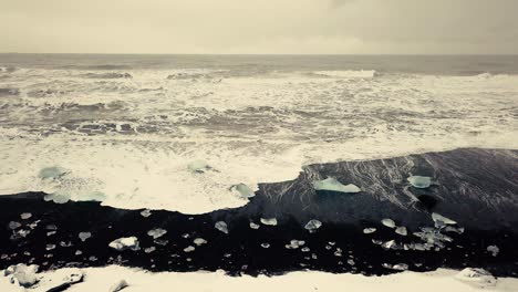 Filmische-Drohnenbewegungen-Zeigen-Einen-Schwarzen-Sandstrand-In-Island,-Der-Von-Einer-Drohne-Bei-Schnee-Gefilmt-Wurde