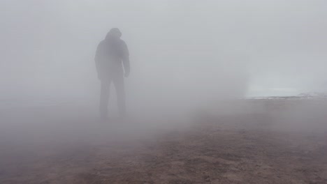 Male-tourist-walk-at-Myvatn-geothermal-area-toward-white-dense-vapor-cloud