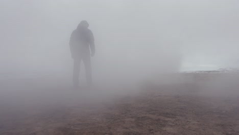 turista masculino camina en el área geotérmica de myvatn hacia una densa nube de vapor blanca