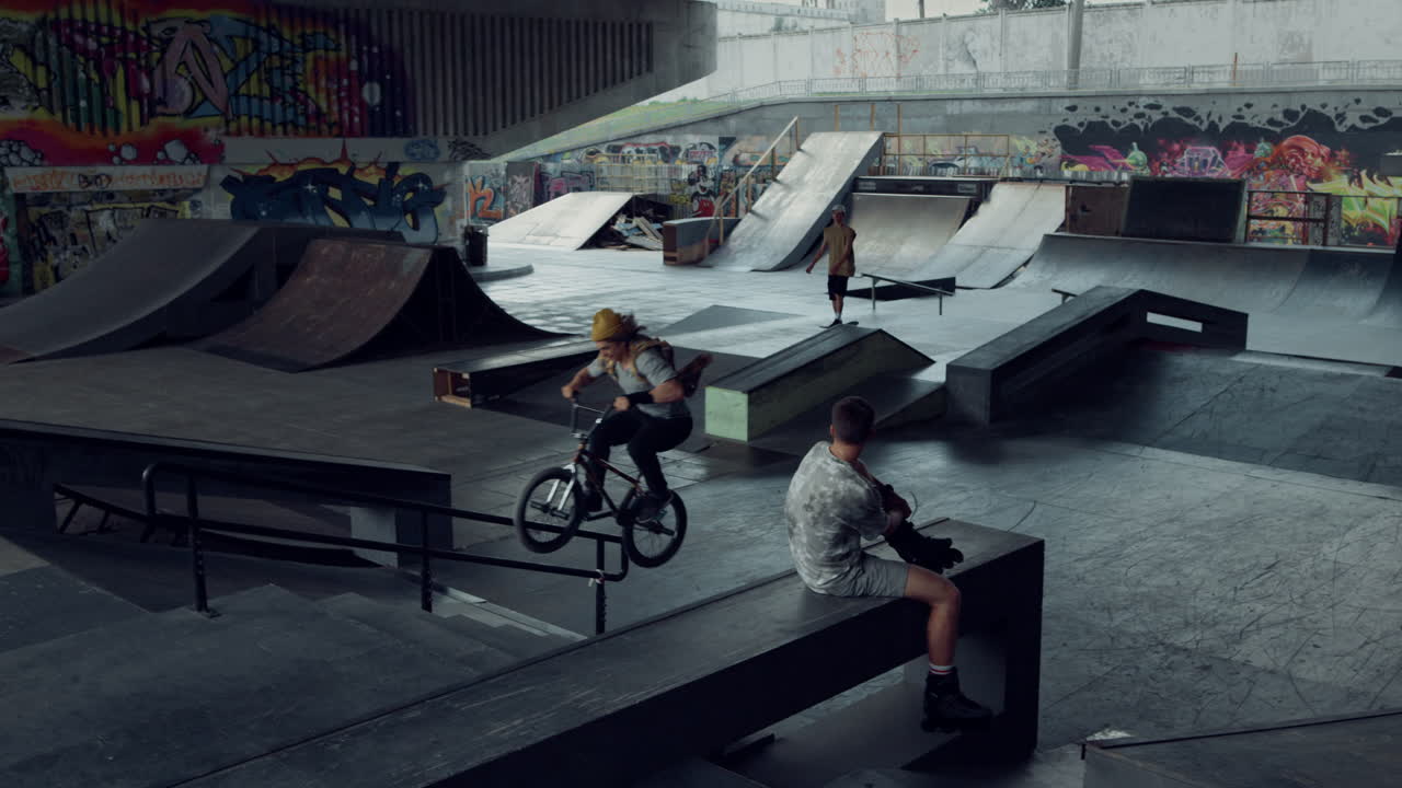 jóvenes adolescentes practicando juntos en bicicleta bmx y tabla de skate en el parque de skate.