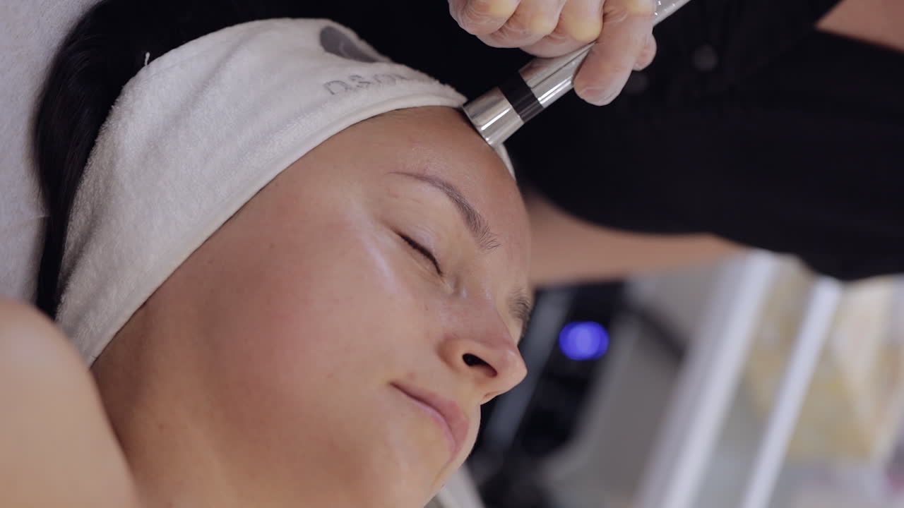 Injectionfree mesotherapy or electroporation beautician makes woman face therapy in clinic salon