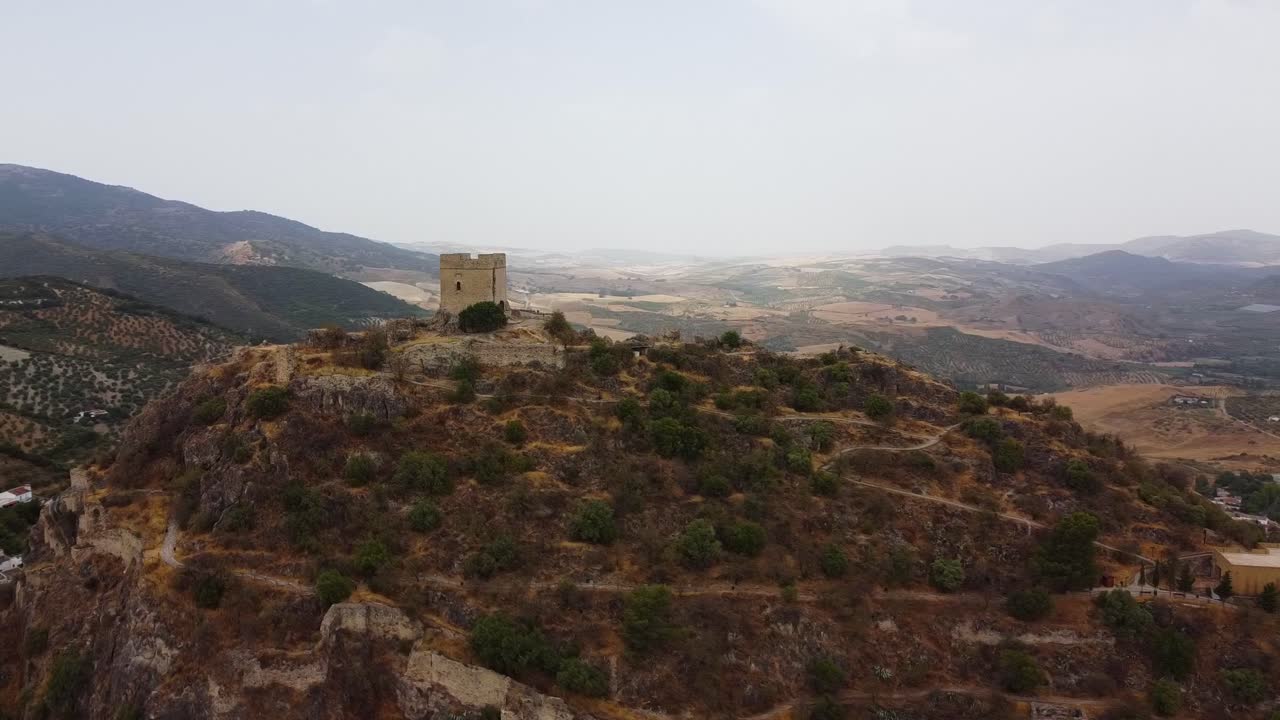 escena aérea de la torre de vigilancia del castillo medieval en la cima de una montaña con casas blancas pueblo tradicional