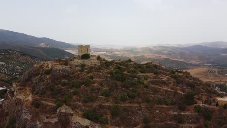 Aerial-scene-of-medieval-castle-watchtower-on-top-of-a-mountain-with-white-houses-traditional-village