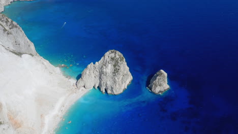 aerial: huge rocks in blue sea and secluded turquoise sand beach in zakynthos island, greece