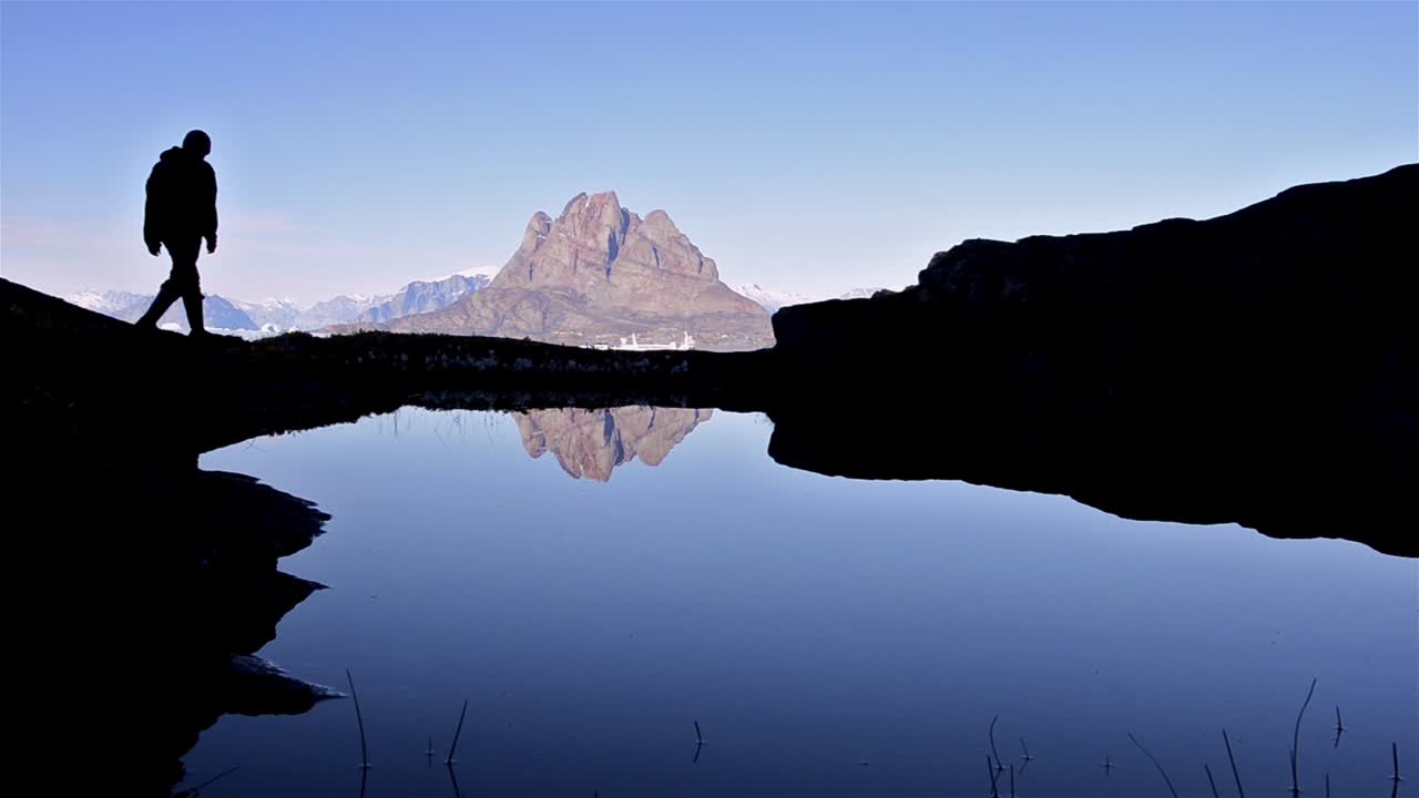 Silhouette di un escursionista di fronte al monte Uummannaq a Qilakitsoq, vicino a Uummannaq, Groenlandia.