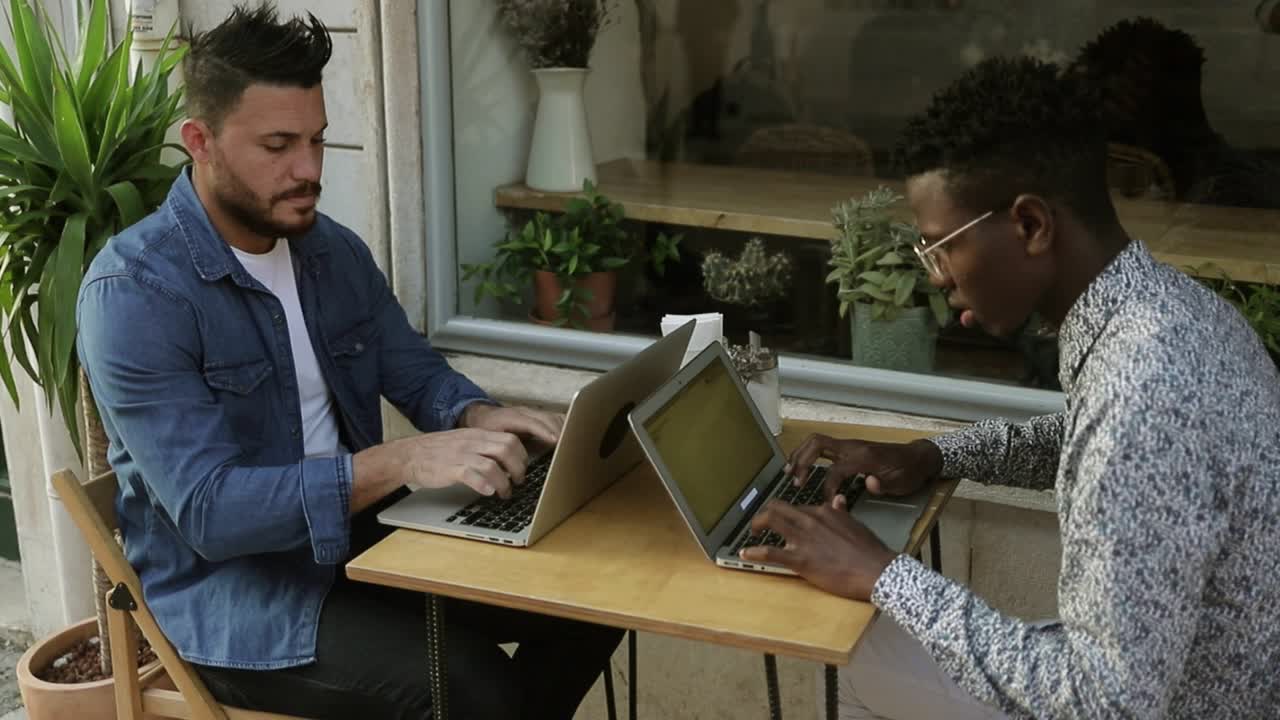 Concentrated young freelancers working at table in cafe