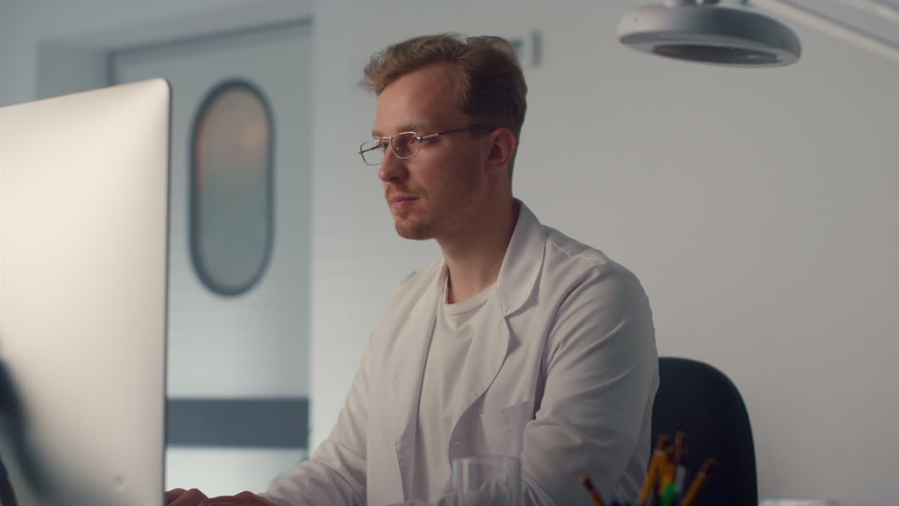 Medicine worker typing computer close up. Man doctor smiling looking camera.