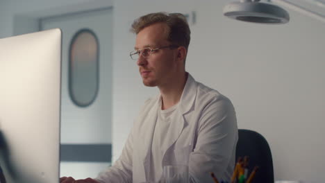 medicine worker typing computer close up. man doctor smiling looking camera.