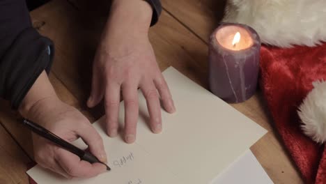 hand writing out christmas greeting cards with candle