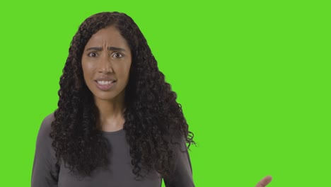 portrait of angry looking woman shouting at camera against green screen