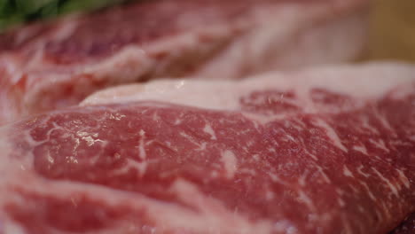 close up of nice fat red meat, fresh cut entrecote beef on table, bokeh