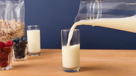 pouring a glass of milk from a pitcher, making breakfast