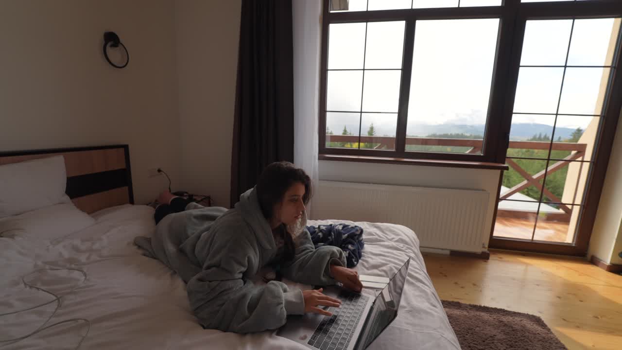 편안한 산 전망 침실에서 노트북에서 일하는 여자