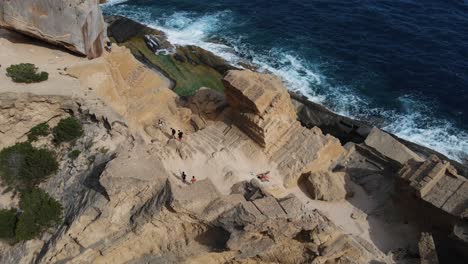 rising aerial of rocky beach coast line and travellers on ibiza