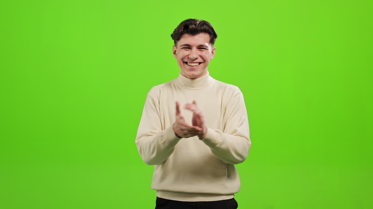 el hombre está de pie y mirando a la cámara. está aplaudiendo y sonriendo. está de pie sobre un fondo verde. pantalla verde. 4k.