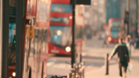 two red busses driving through london with people