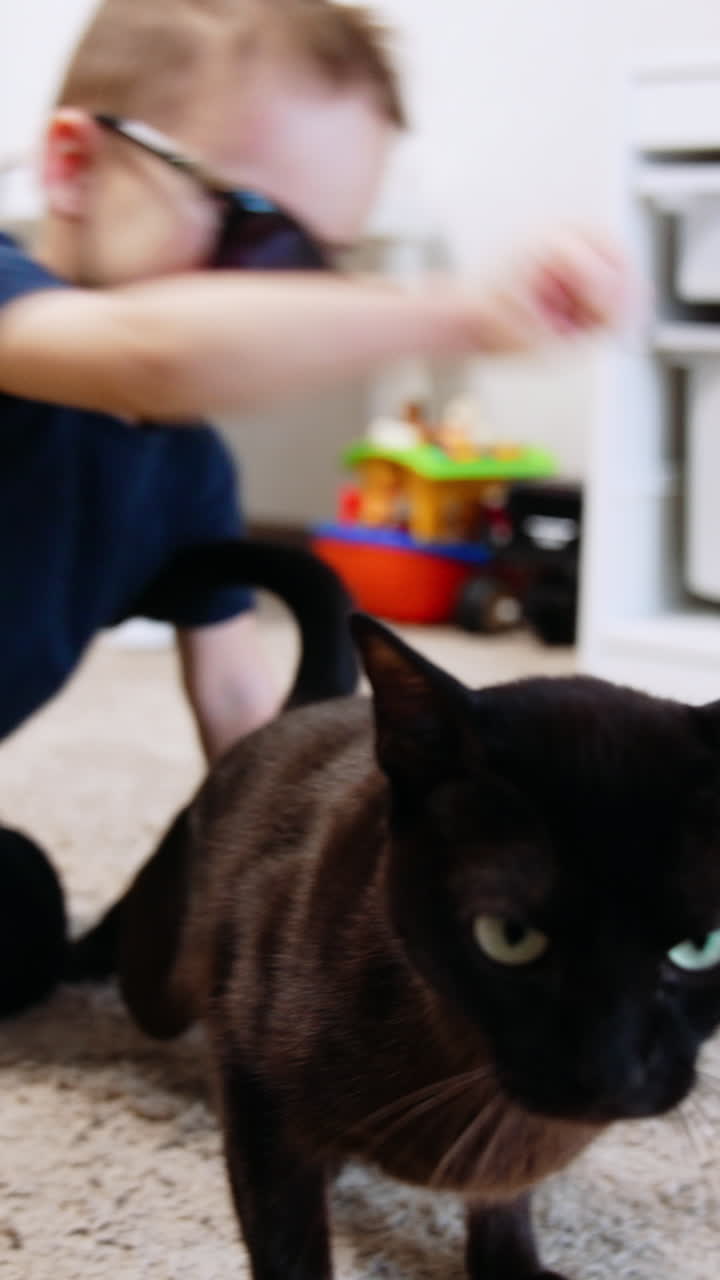 Funny boy in sunglasses playing indoor. Cheerful kid having fun on a floor. Vertical video