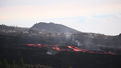 small settlement in mountainous valley with erupting volcano