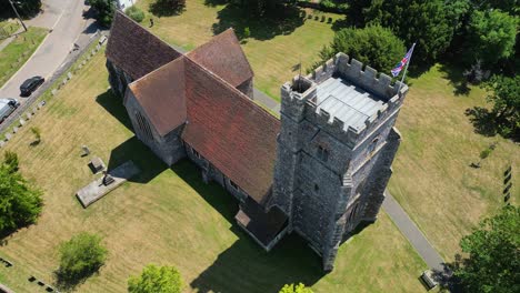 An-arc-shot-of-St-Mary's-church-in-Chartham,-with-a-union-flag-clearly-flying-from-the-church-tower