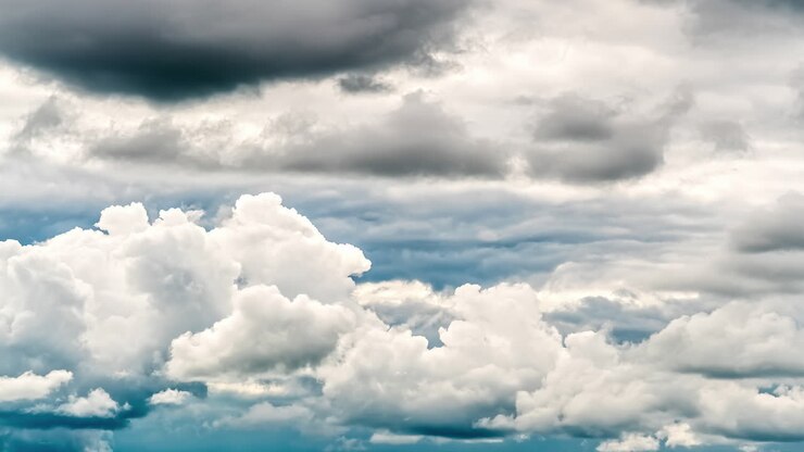 Time lapse shot of dense white and black flying clouds on sky with sunlight in background