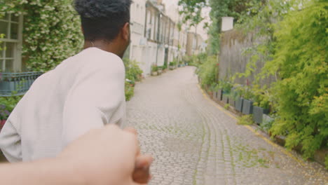 point of view shot of young man leading woman through city street by the hand