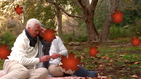 animation of red autumn leaves falling over happy senior caucasian couple in park