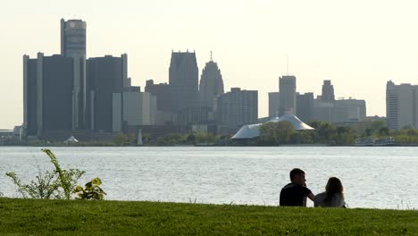 jovem casal sentou-se em frente à paisagem urbana de detroit