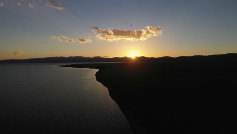 Epic-cinematic-aerial-drone-shot-of-the-sun-setting-behind-the-mountains-surrounding-the-Song-Kol-lake-in-Kyrgyzstan