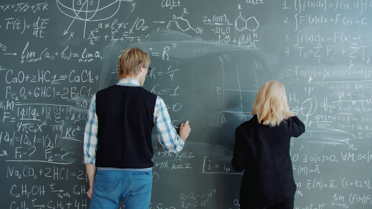 Students working on a chalkboard filled with equations and formulas