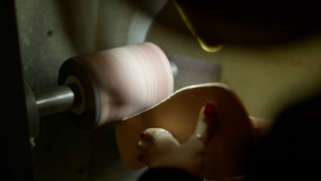 Female-shoemaker-shaping-leather-sole-form-on-old-workshop-machine,-close-up-shot
