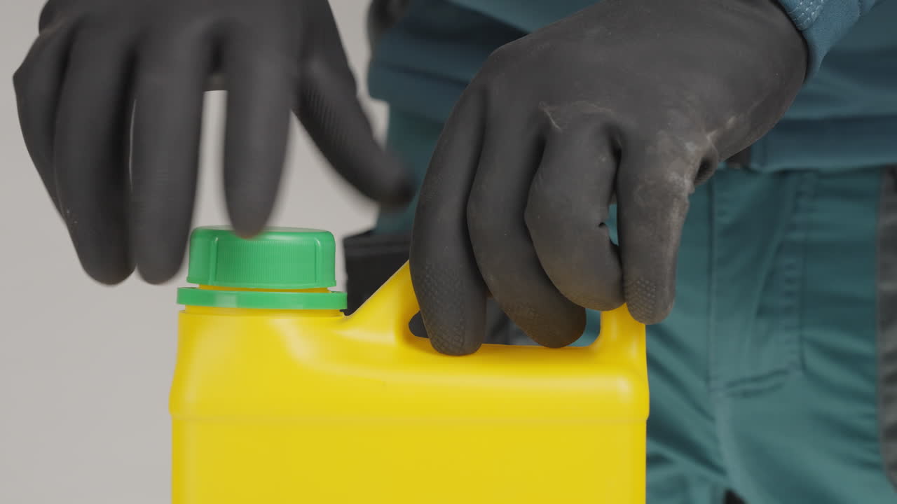 persona con guantes manejando un recipiente de plástico amarillo